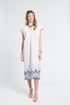 Woman wearing a white caftan with blue lace details on a white background