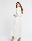 Woman wearing a white maxi dress with white heels on a white background