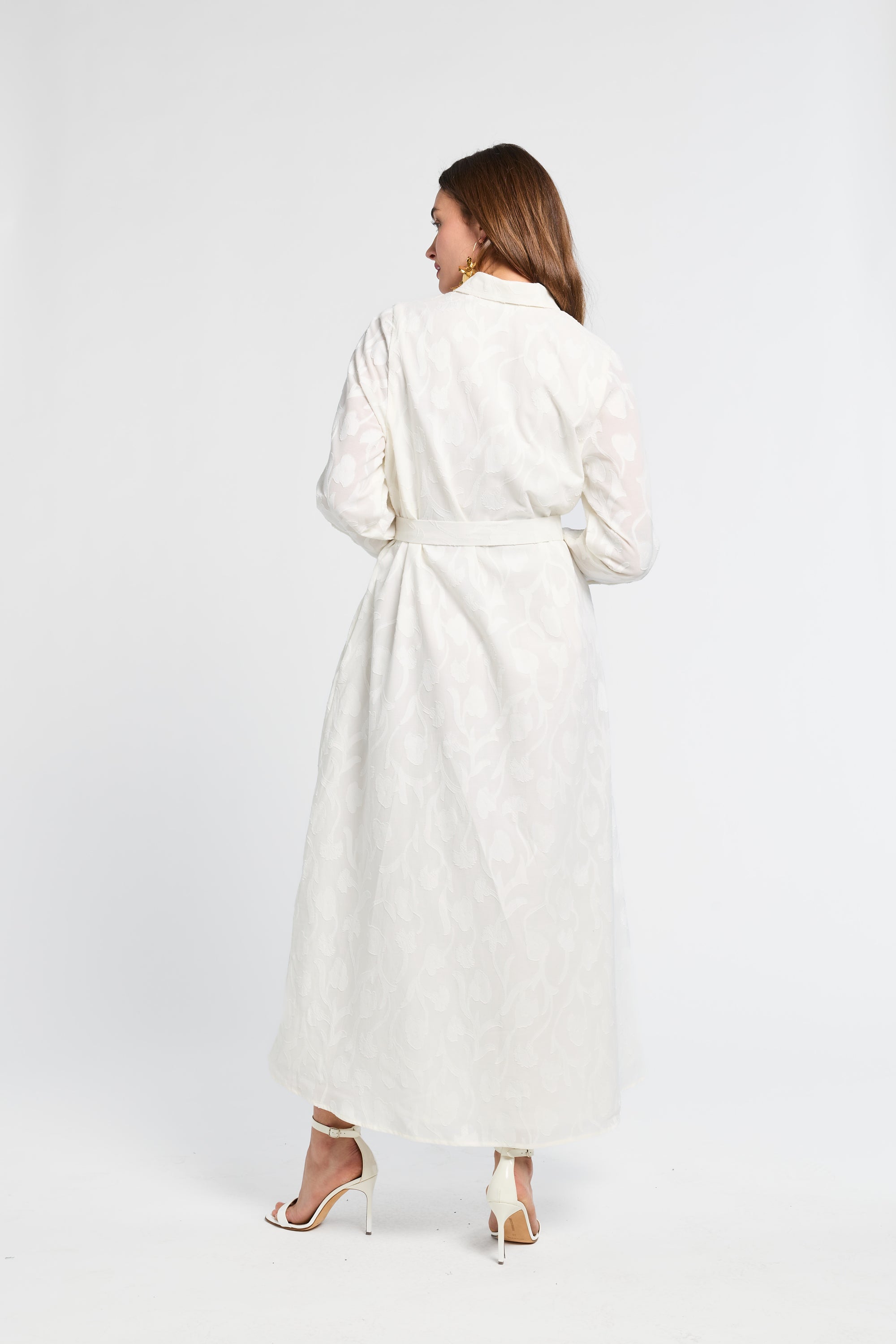 Woman with brown hair wearing a white dress against a white background