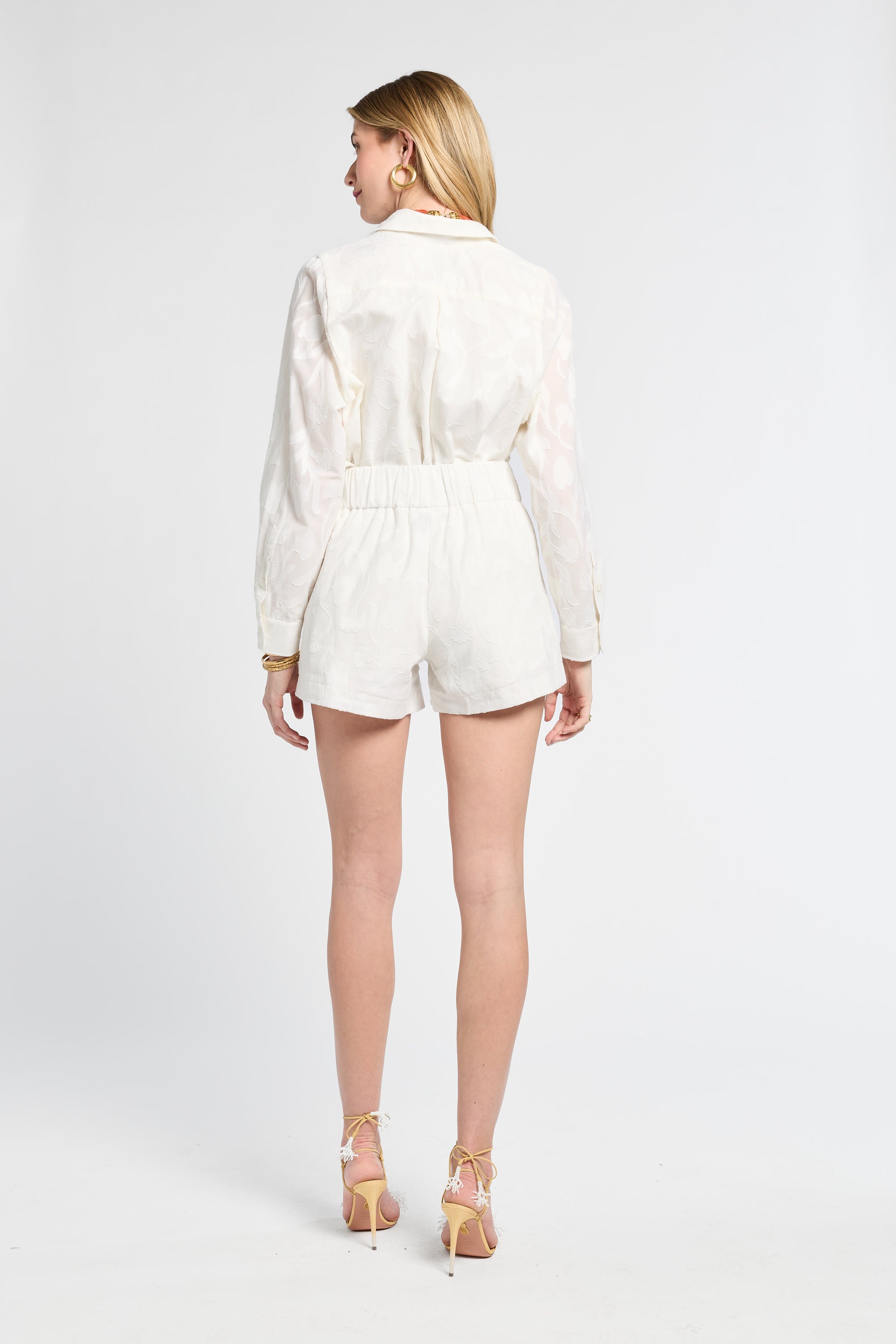 Woman with blonde hair modeling floral white shorts on a white background