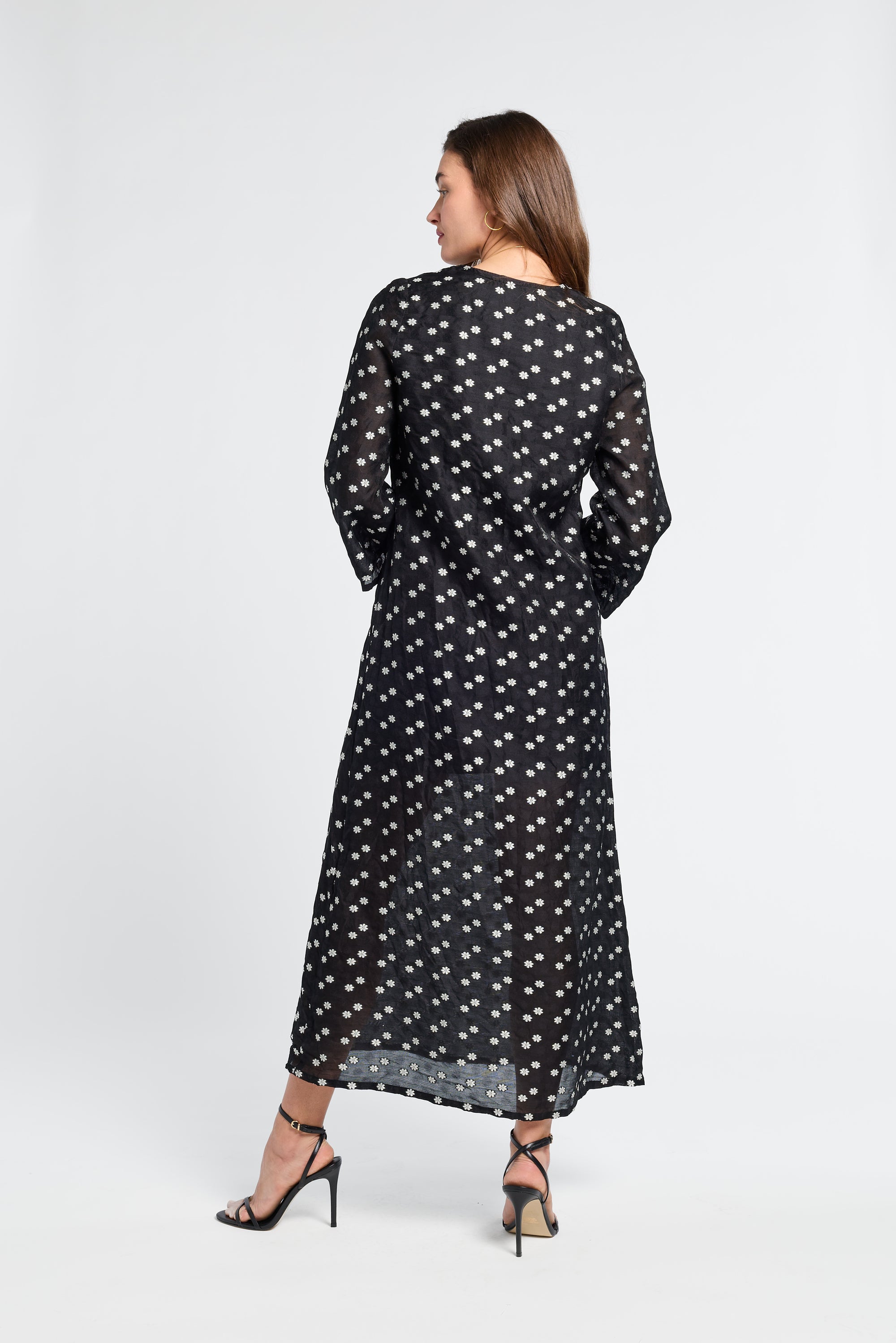 Woman wearing a sheer black floral dress on a white background