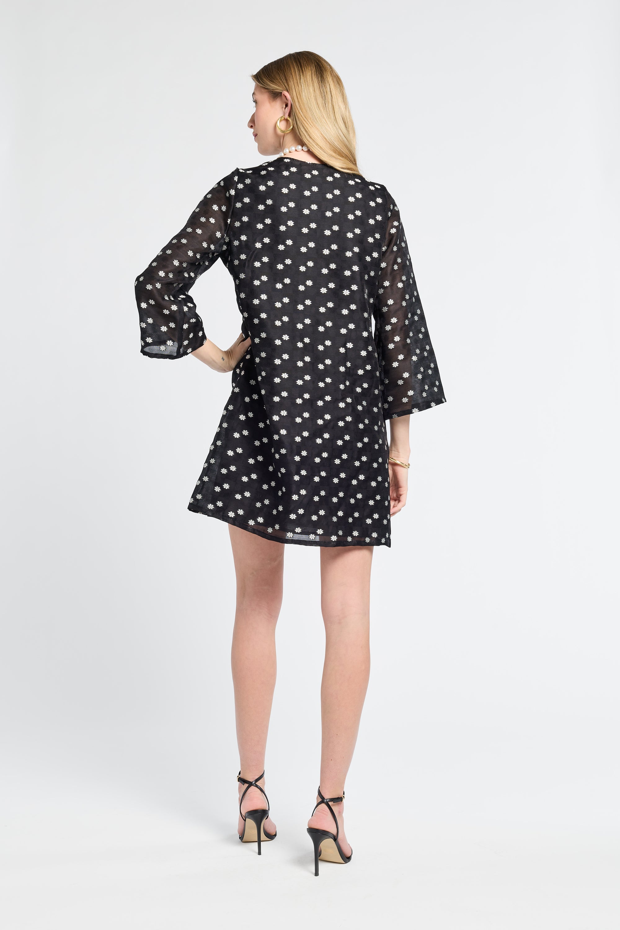 Woman modeling a sheer black dress with small white flowers on a white background