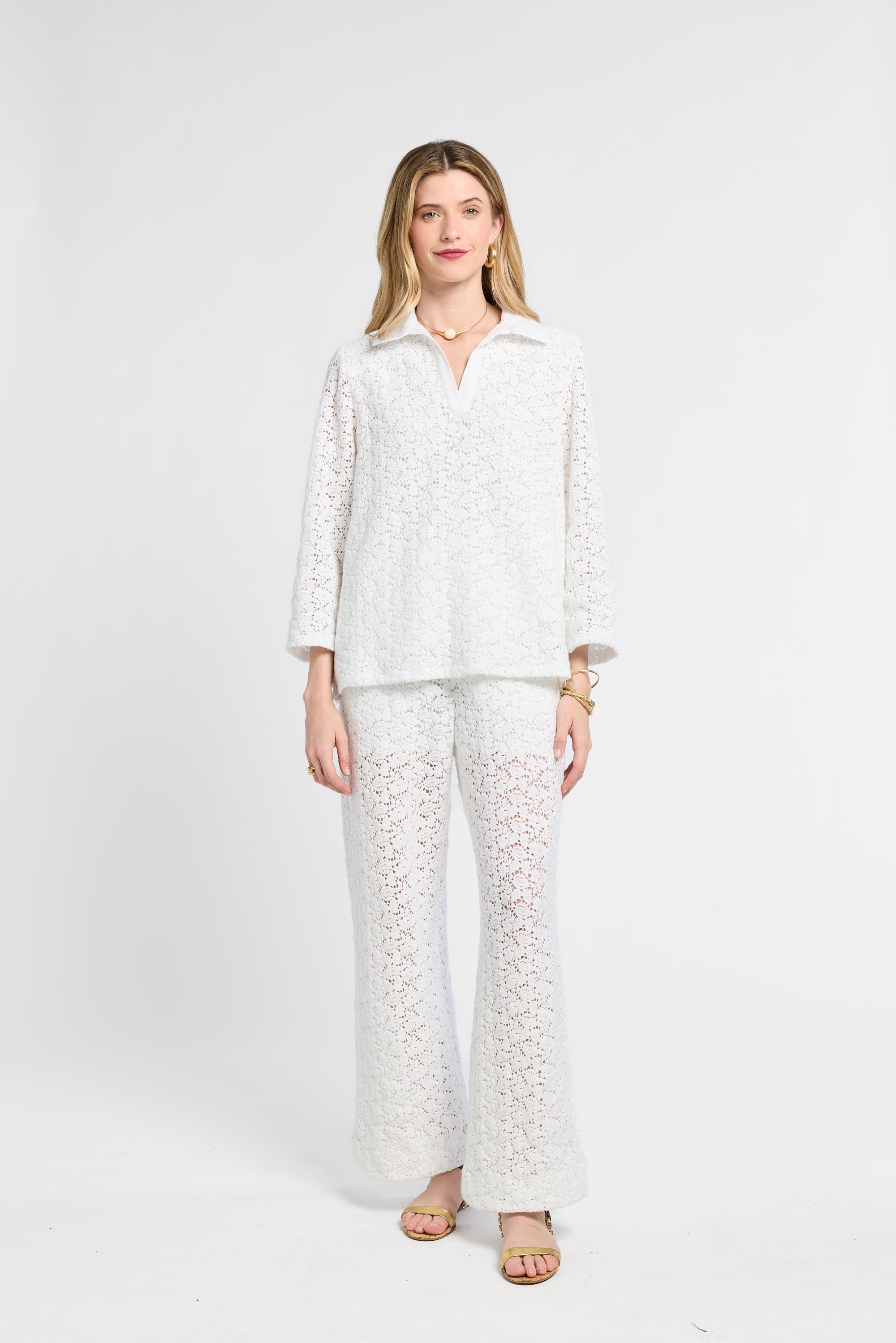 Woman wearing a white lace tunic on a white background with flats