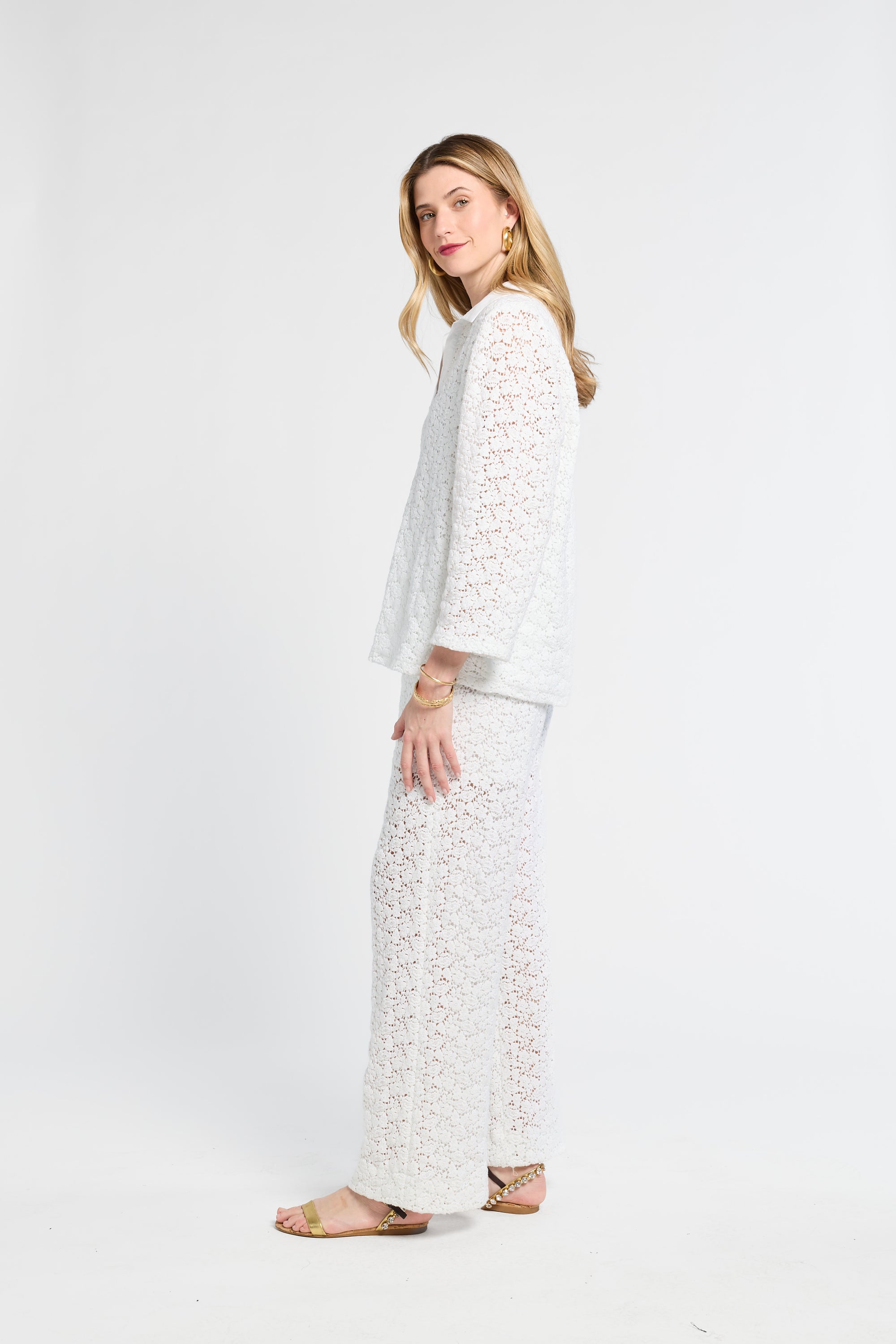 Woman wearing white lace pants and blouse against a white backdrop