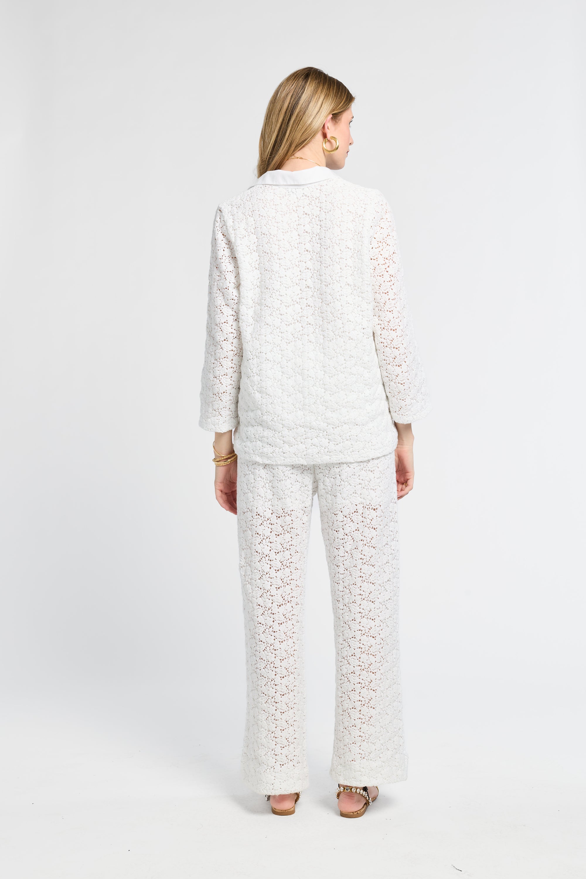 Lady modeling a white lace tunic and pants against a white background
