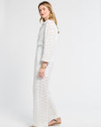 Woman modeling white pants with lace details on a white background