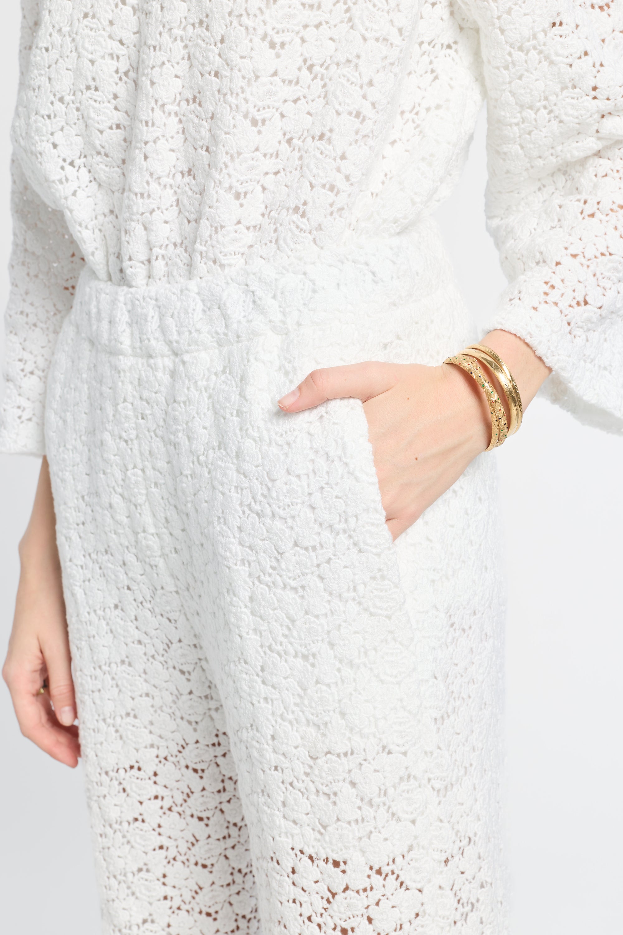 White textured pants with a hand in the pocket on a light gray background