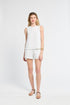 Woman wearing a white sleeveless blouse and shorts on a white background