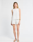 Woman wearing a white sleeveless blouse and shorts on a white background
