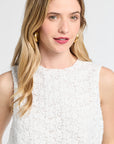 Woman wearing a lace white sleeveless blouse with a plain background