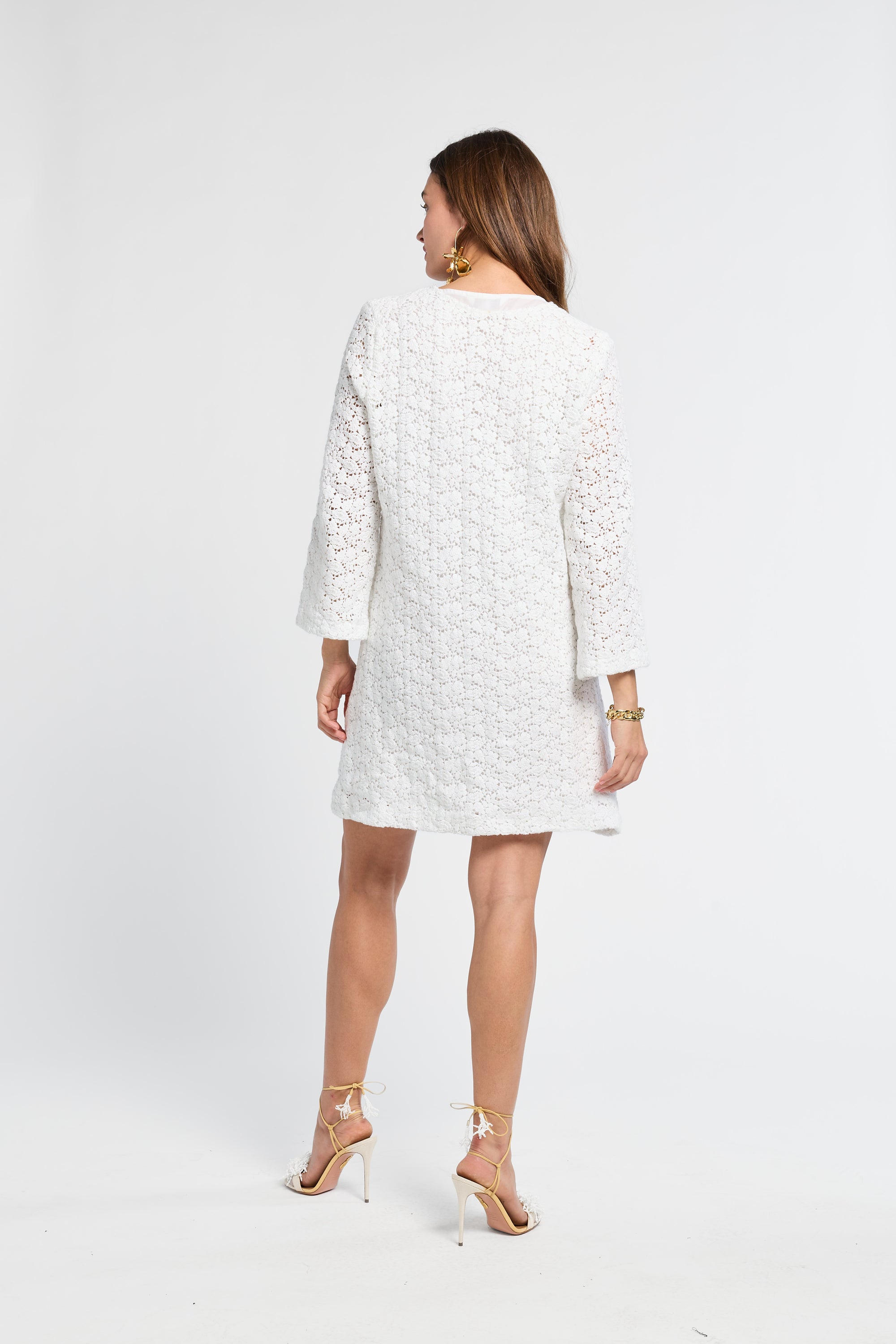 Woman wearing a white lace dress and heels on a white background