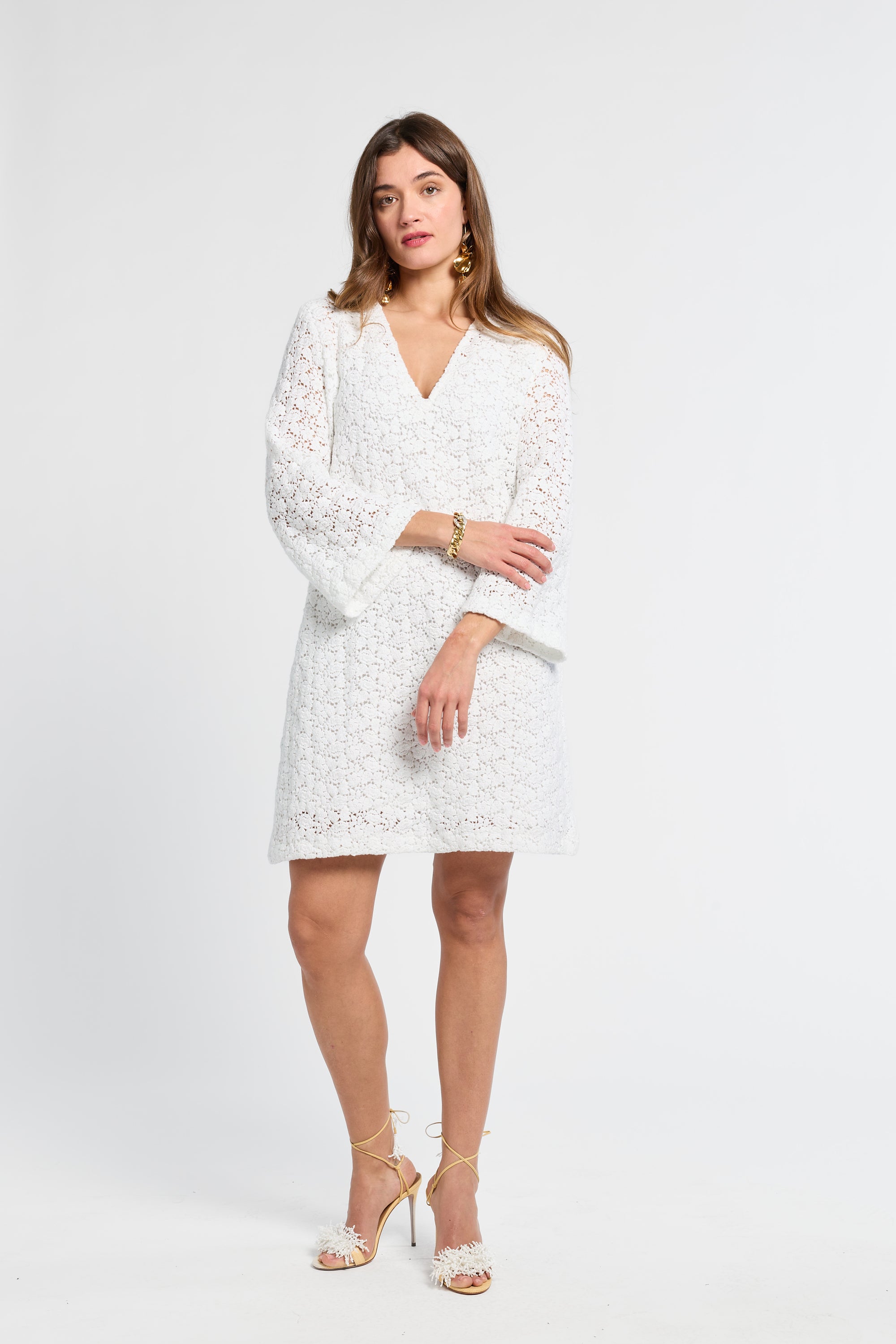 Woman wearing a v-neck white lace dress on a white background