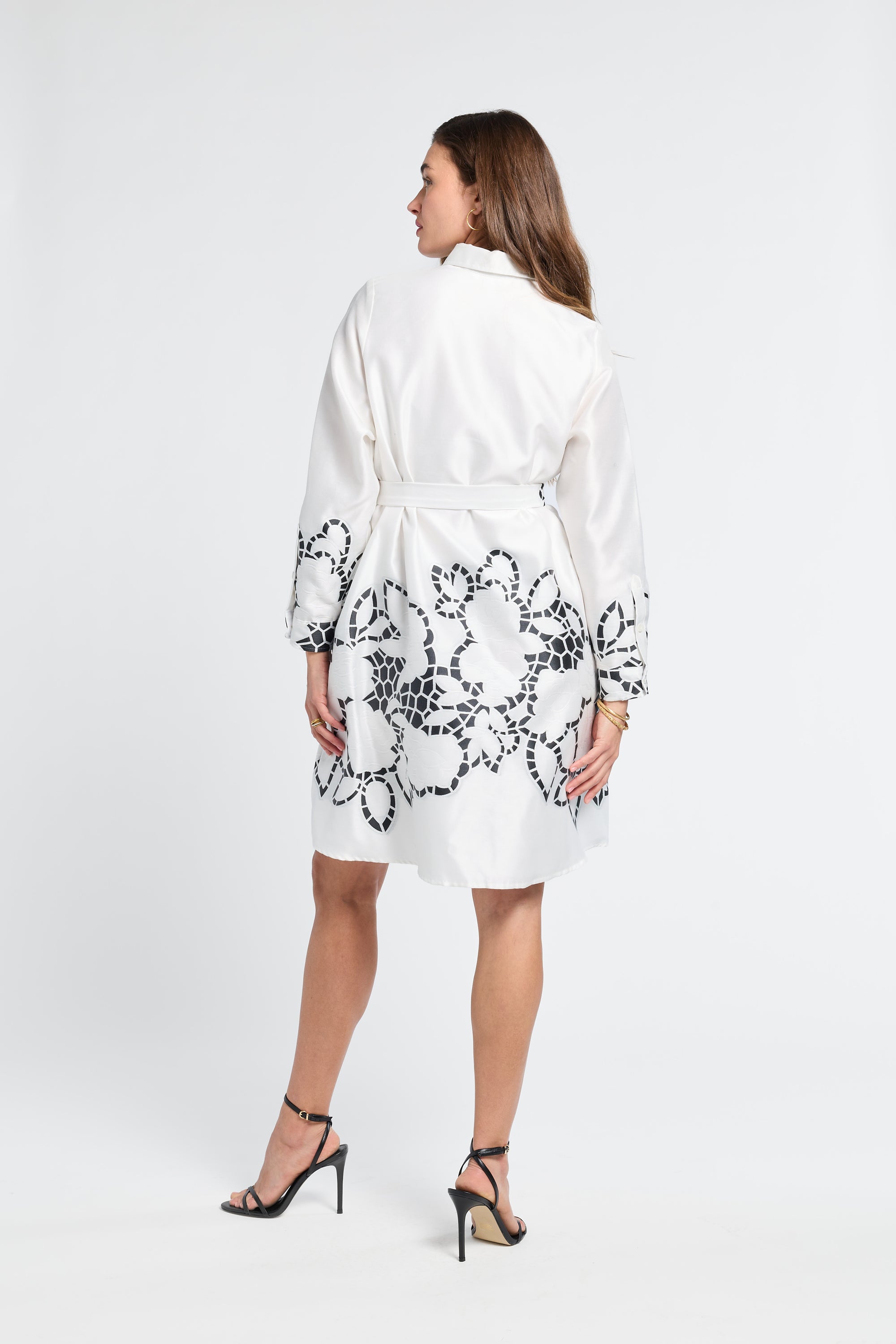 Woman wearing a white dress with black floral patterns on a white background