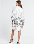 Woman wearing a white dress with black floral patterns on a white background