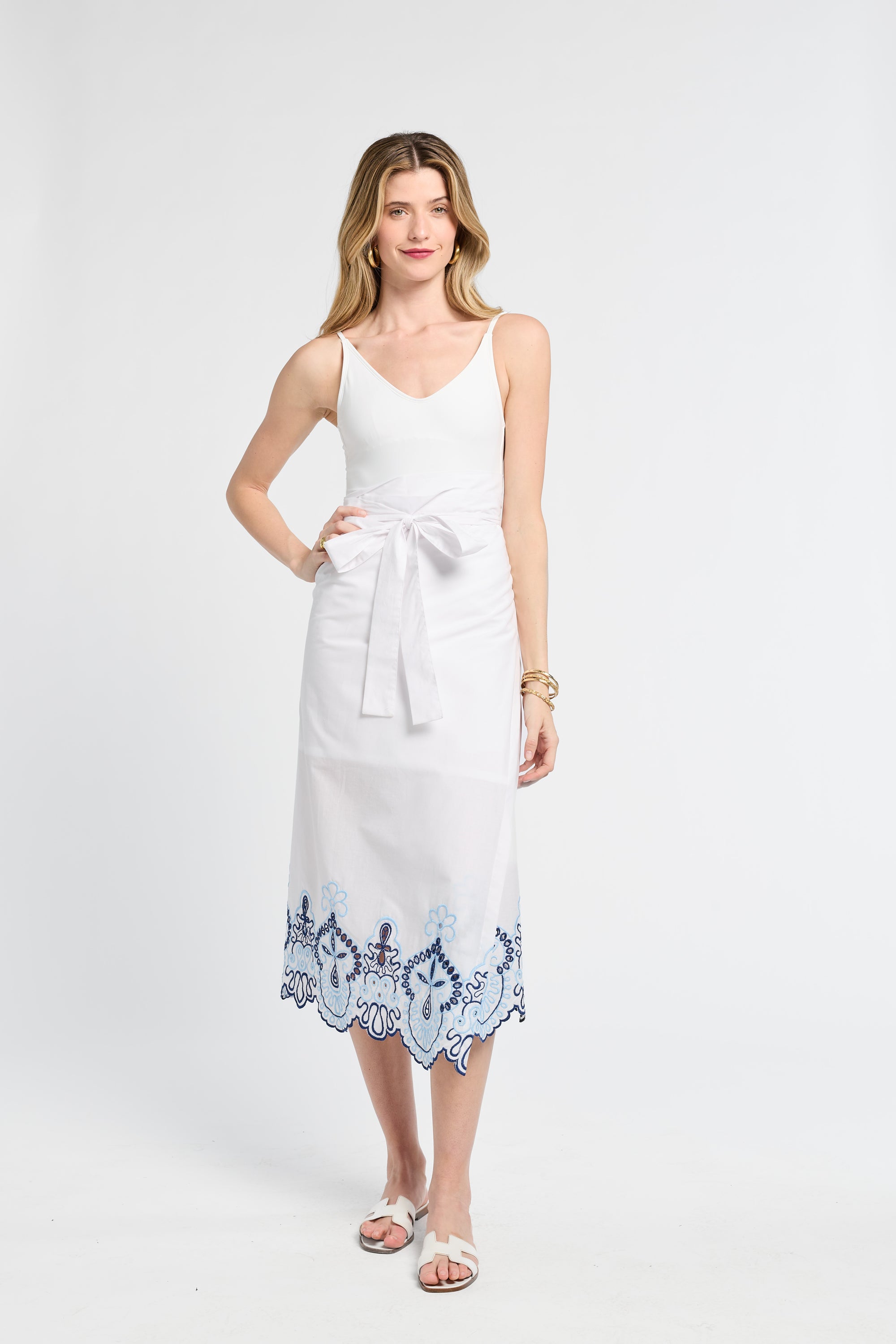 Woman wearing a white pareo with blue lace trim on a white background