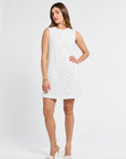 Woman wearing a white sleeveless lace dress on a white background