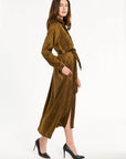 A woman modeling the Golden Umber Eleanor Shirt Dress with a tied sash and black heels, side view, photographed against a plain white studio background.