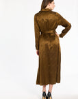 A woman modeling the Golden Umber Eleanor Shirt Dress with a tied sash and black heels, back view, photographed against a plain white studio background.