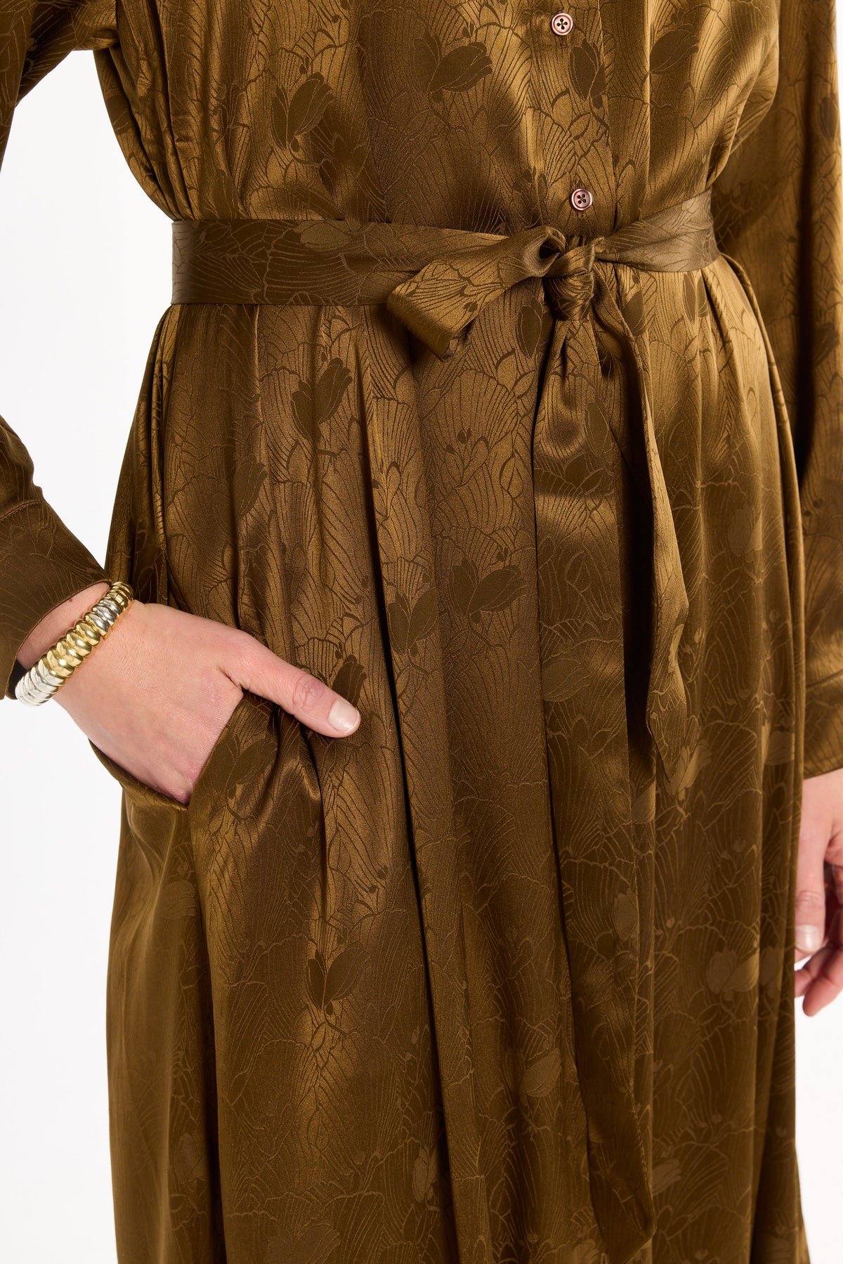 Close-up of the tied sash, pocket, buttons, and tonal floral texture of the Golden Umber Eleanor Shirt Dress, photographed against a plain white studio background.
