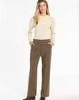 A woman modeling the Tobacco Tweed Ellis Pants with a cream sweater and brown loafers, front view with hands in pockets, photographed against a plain white studio background.