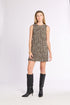 Woman wearing a tan and black plaid tweed dress with black boots against a white background