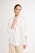 A woman wearing a white, long-sleeved, button-up shirt with a collar.
