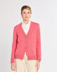 Woman wearing a pink cardigan with gold buttons on a white background