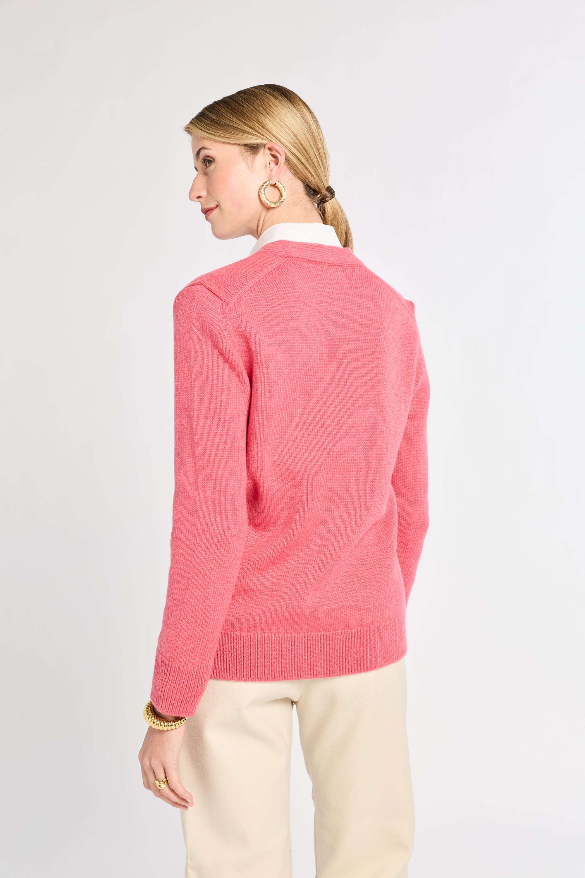 Woman wearing a pink sweater on a plain background