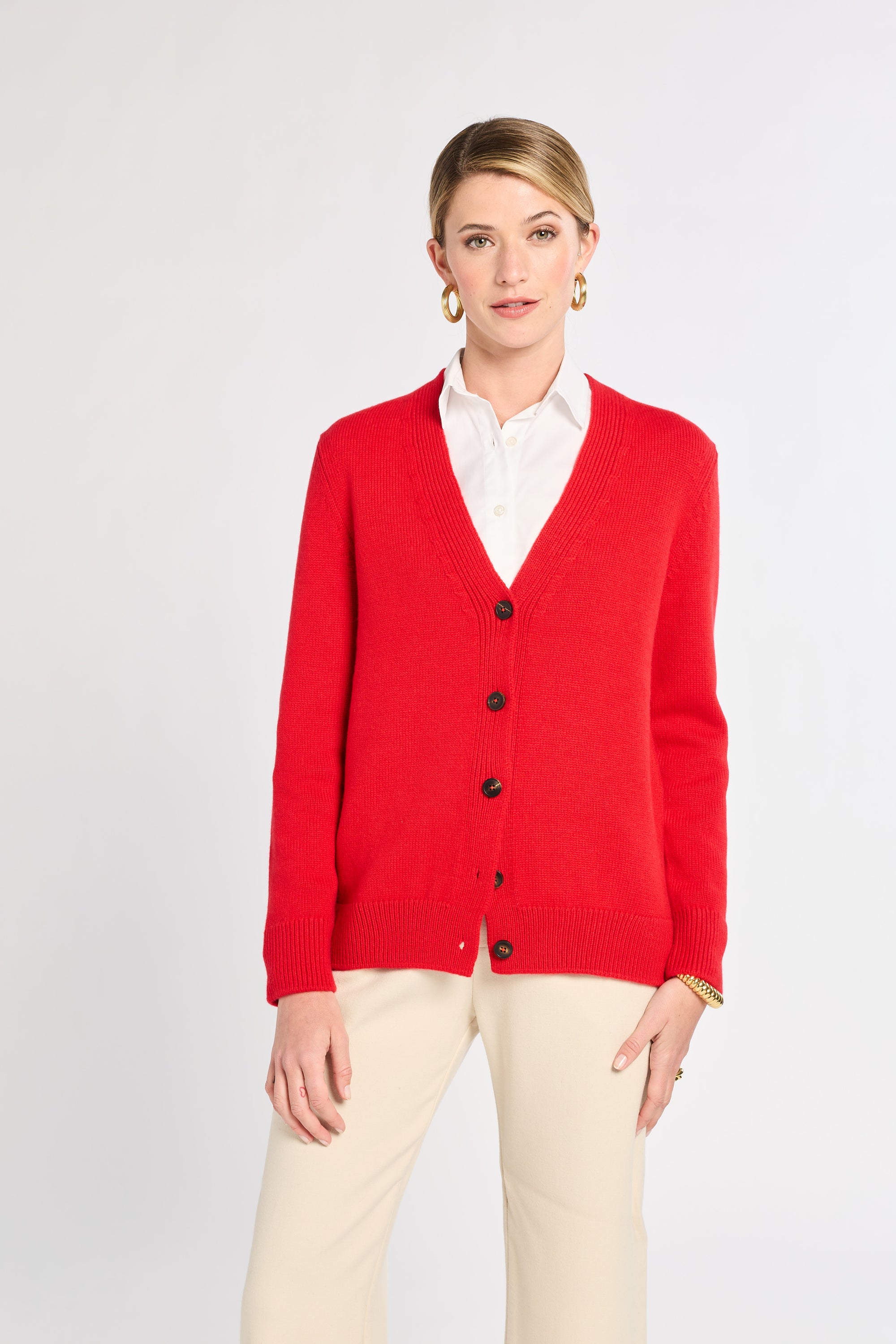 Woman wearing a red cardigan over a white shirt on a light gray background