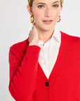 Woman wearing a red cardigan over a white shirt on a light gray background