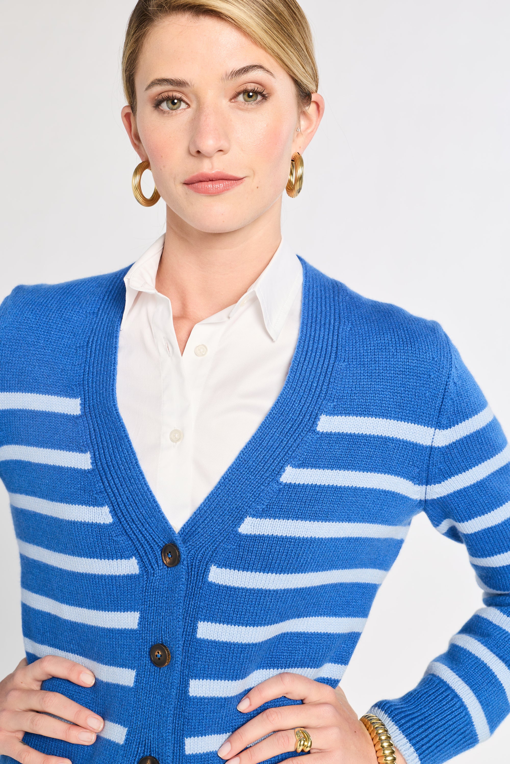 Woman wearing a blue and white striped cardigan on a plain background