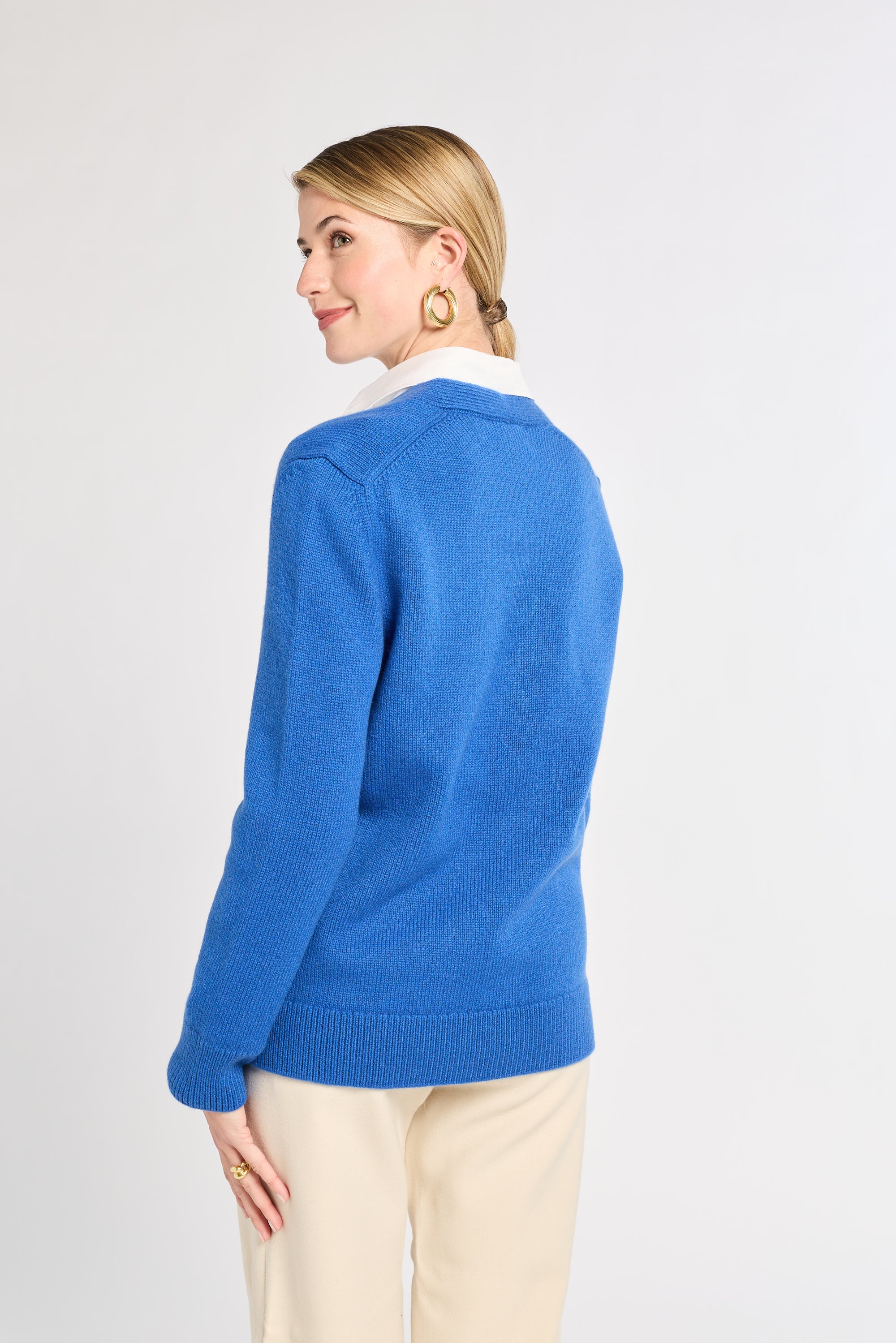 Woman wearing a blue sweater with a white collar on a light gray background