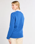 Woman wearing a blue sweater with a white collar on a light gray background