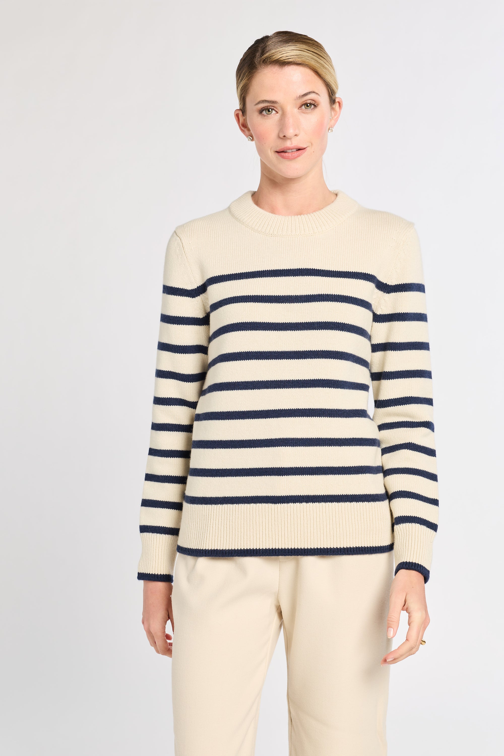 Woman wearing a cream and navy striped sweater on a white background