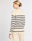 Woman wearing a cream and navy striped sweater on a plain background