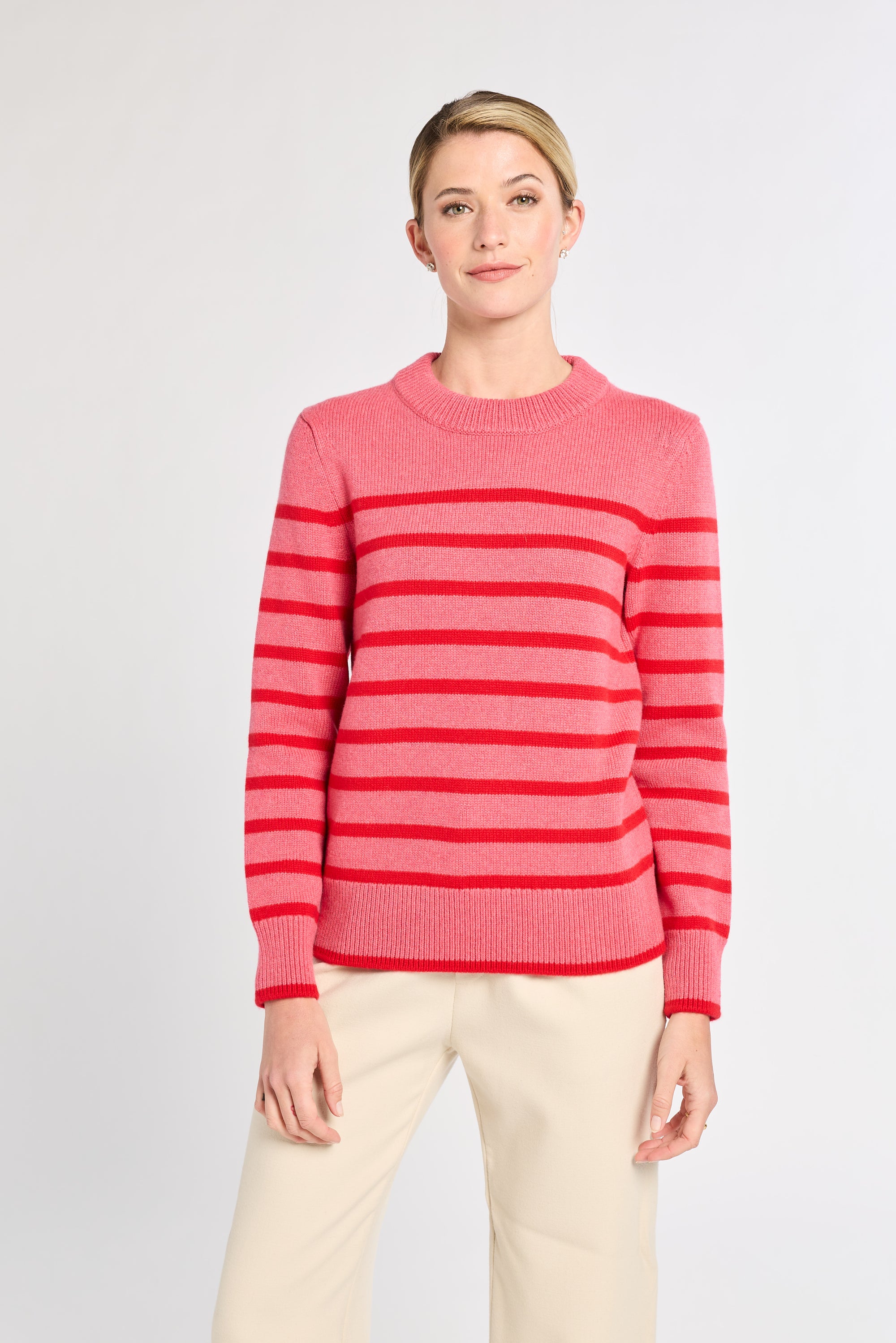 Woman with pink sweater with red stripes with white background. 