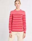 Woman with pink sweater with red stripes with white background. 