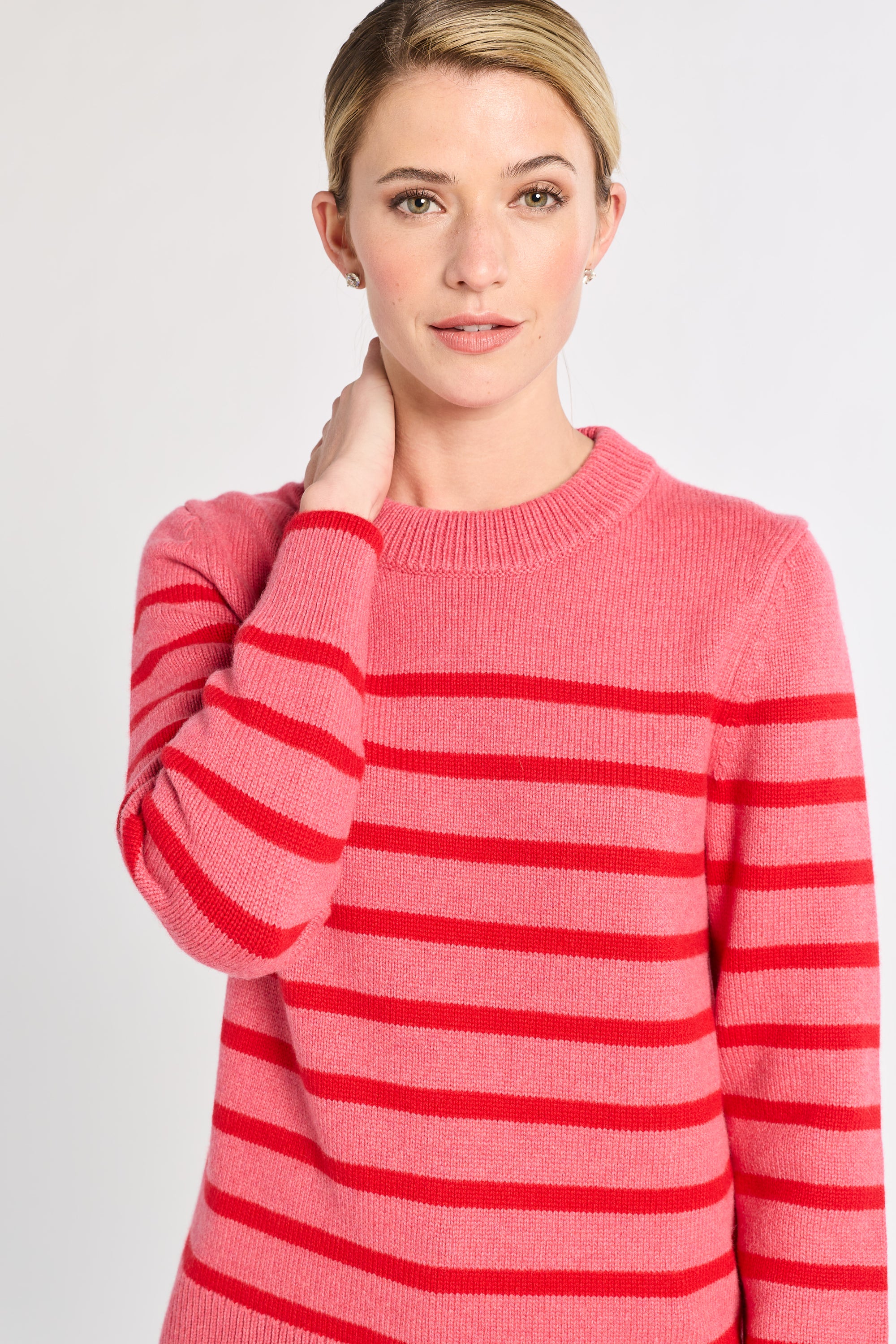 Woman wearing a pink and red striped sweater on a plain background