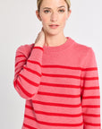 Woman wearing a pink and red striped sweater on a plain background