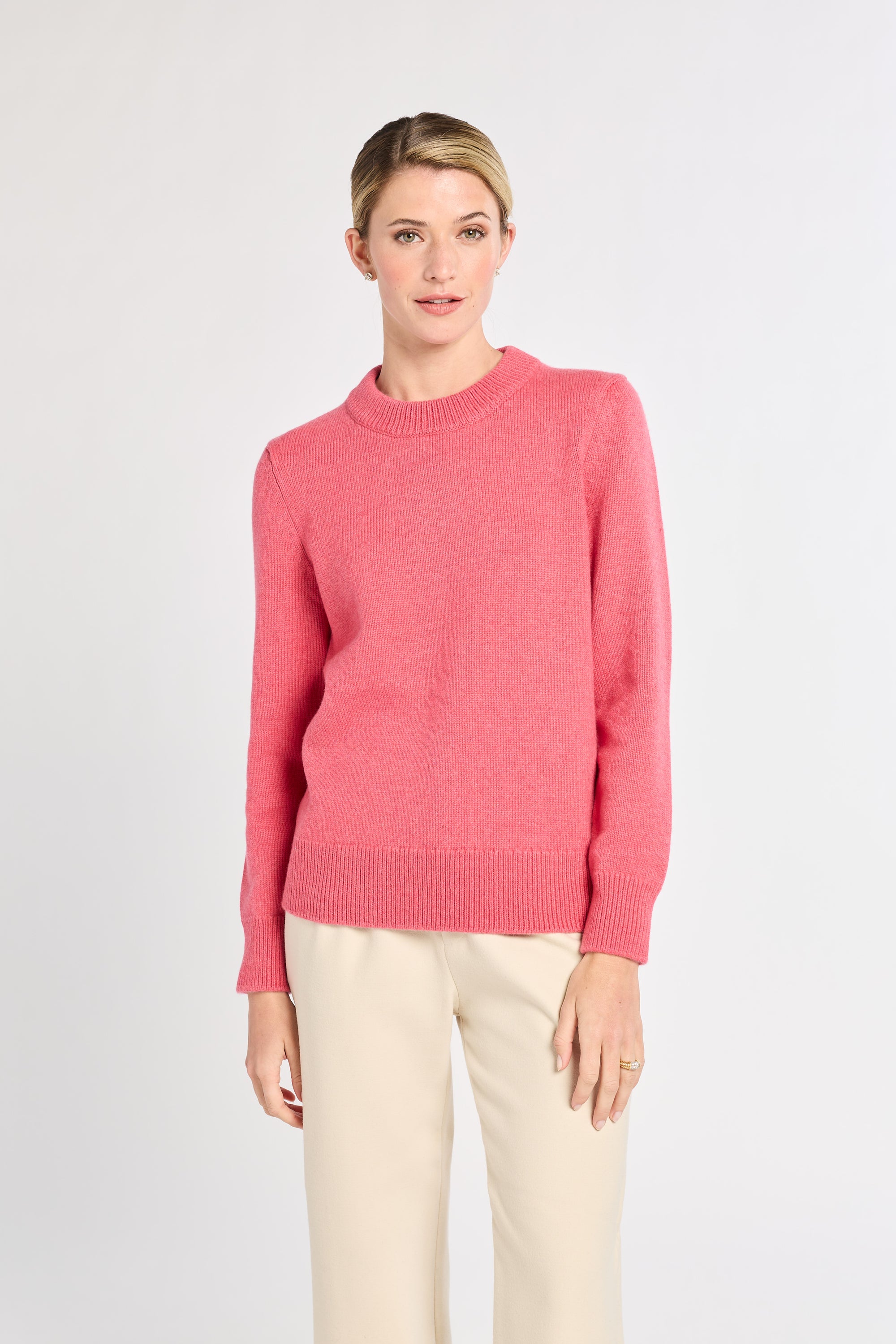 Woman with pink sweater on with white background. 