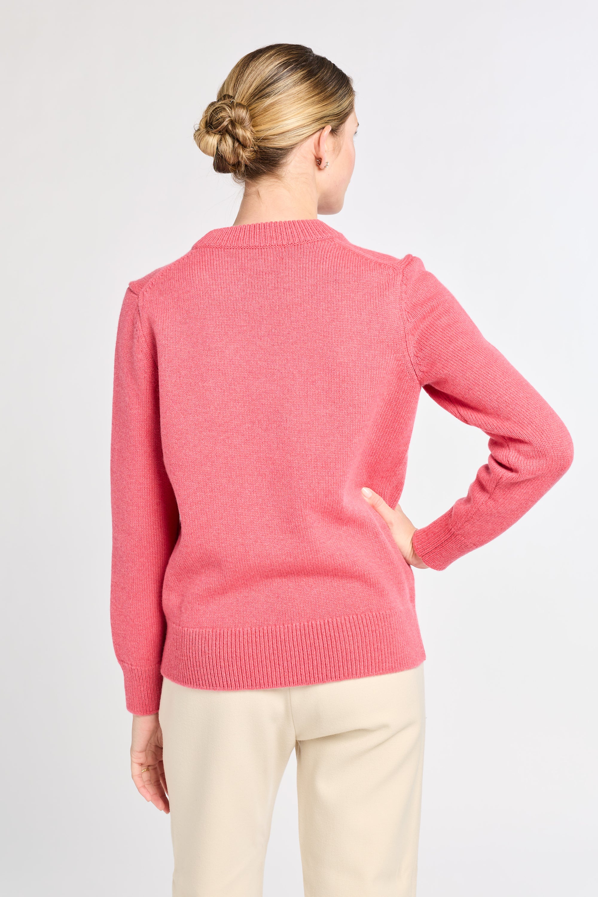 Woman wearing a pink sweater on a plain background