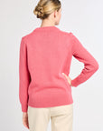Woman wearing a pink sweater on a plain background