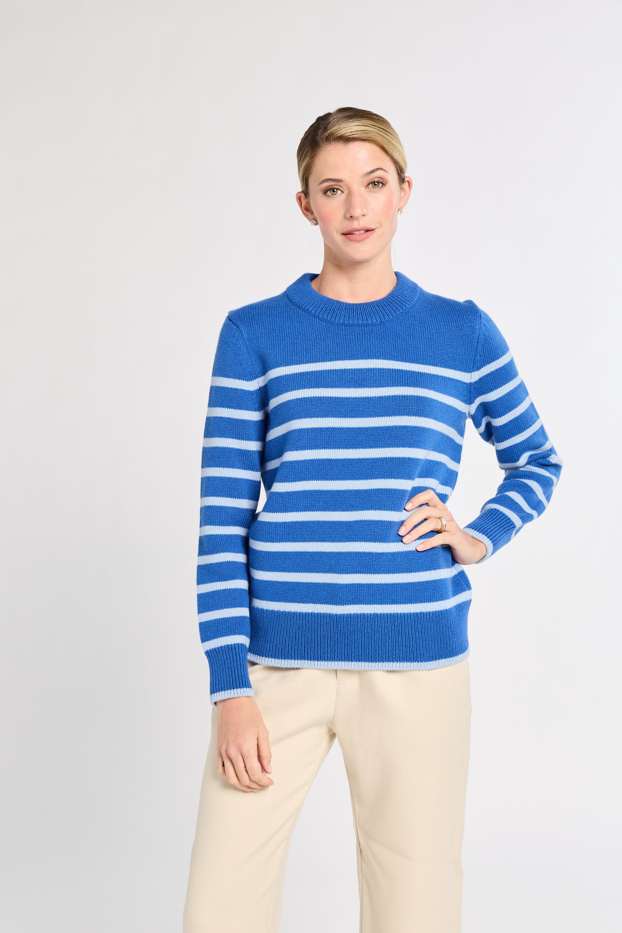 Woman with cobalt with light blue stripe sweater with white background. 