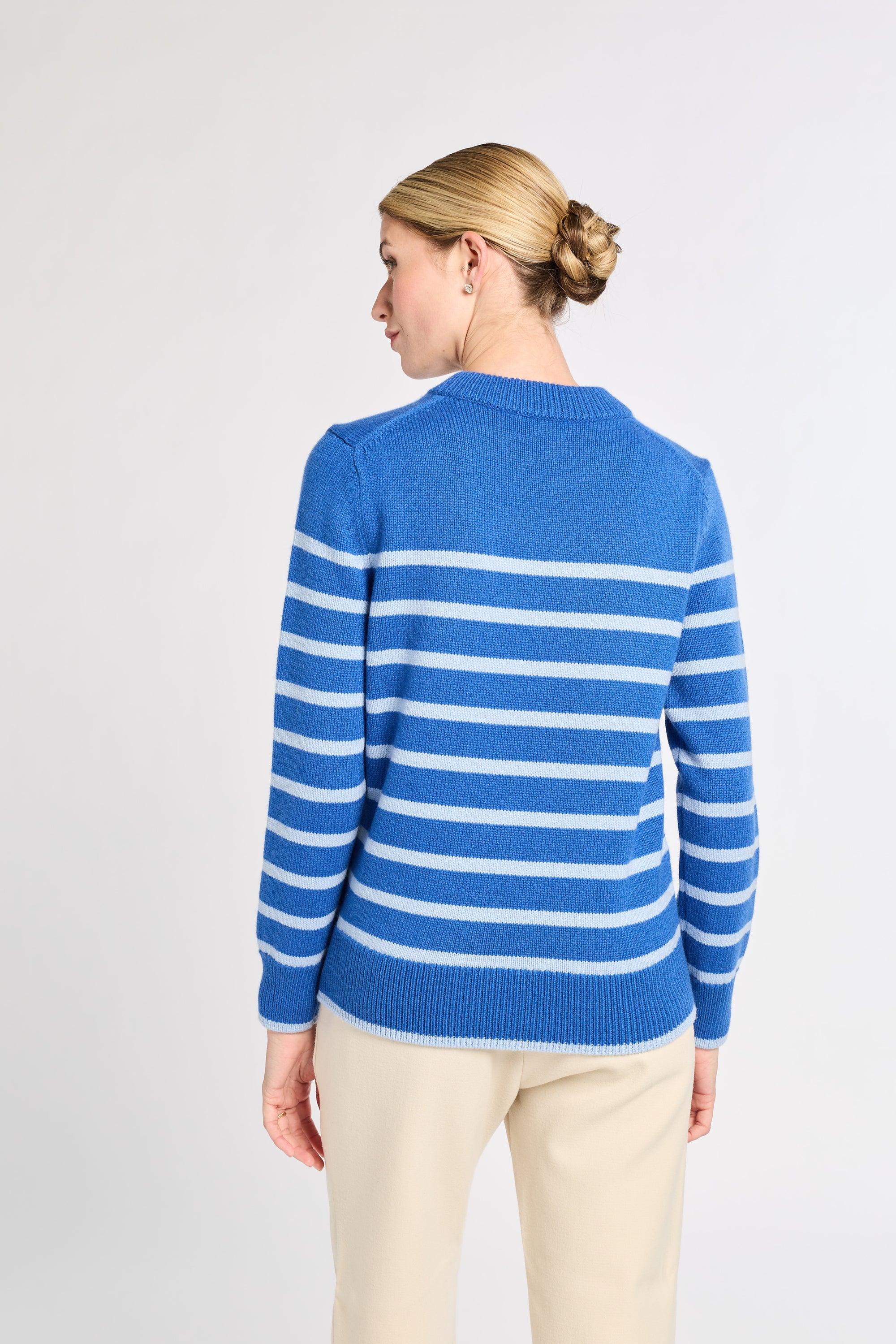 Woman wearing a blue and light blue striped sweater on a light gray background