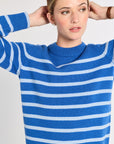 Woman wearing a blue and light blue striped sweater against a light background