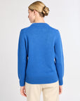 Woman wearing a blue sweater and beige pants on a white background