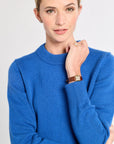 Woman with a blue sweater on with a white background.
