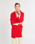 Woman wearing a red coat over a white shirt on a light gray background