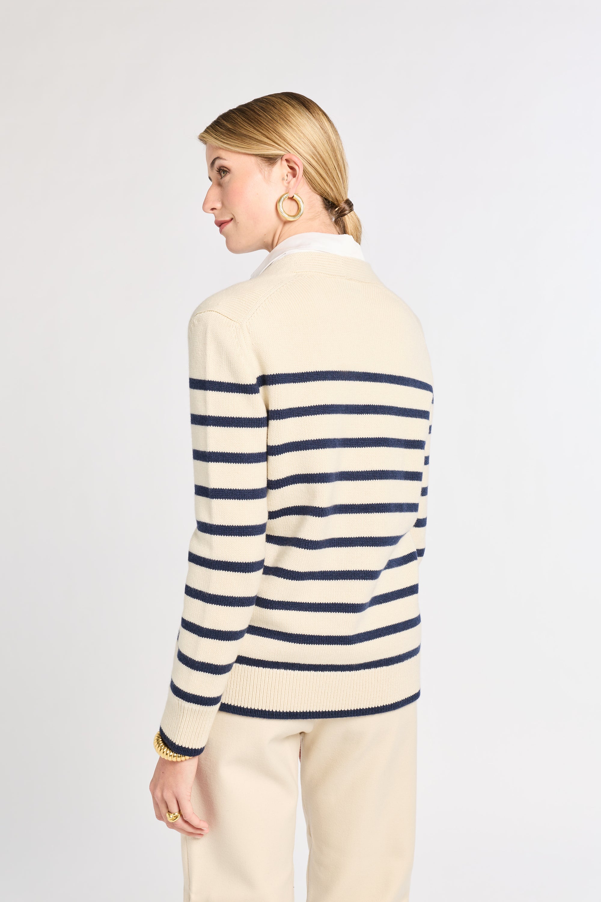 Woman wearing a cream and navy striped sweater on a white background
