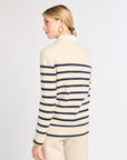 Woman wearing a cream and navy striped sweater on a white background